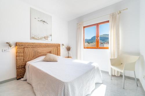 a white bedroom with a bed and a window at Miramar in Artá