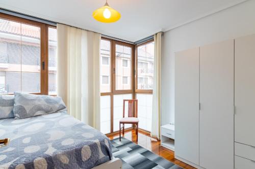 a bedroom with a bed and large windows at Piso con piscina in Bádames