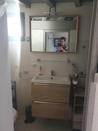 a man taking a picture of a bathroom with a sink at Maison du Pâtre in Urbanya
