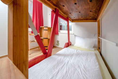 a small room with a bed and red curtains at Ferienwohnung Storchennest in Neuendorf am See