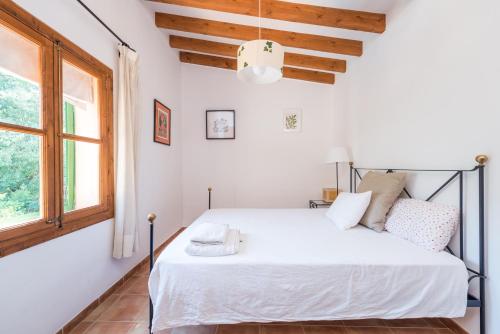 a bedroom with a white bed and a window at Can Guixa in Sóller