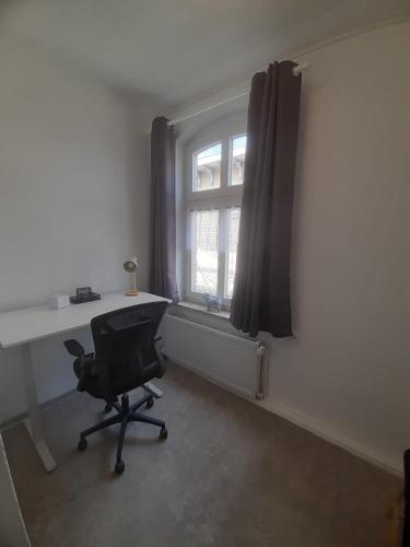 a desk and a chair in a room with a window at Meeresleuchten 2 in Emden