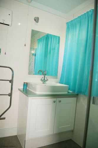 a bathroom with a sink and a blue shower curtain at Bryn Rhedyn Fairbourne in Fairbourne