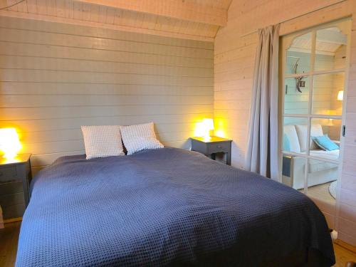 a bedroom with a blue bed with two lamps at Vakantiewoning Moerweie GR04 in Grijpskerke