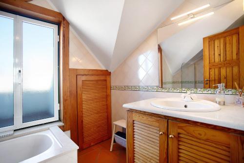 a bathroom with a sink and a tub and a mirror at A Casa da Concha in São Pedro de Moel