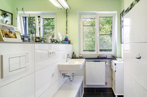 a white bathroom with a sink and windows at Ferienwohnung Refugium Nest in Sigmaringen
