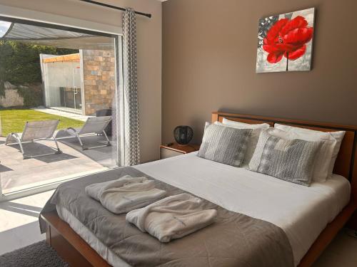 a bedroom with a bed and a large window at Villa Mila Piscina e Jacuzzi in Salir de Matos