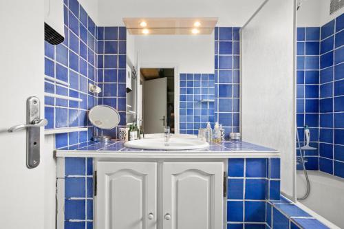 a blue tiled bathroom with a sink and a mirror at Hébergement Climatisée Cogolin in Cogolin