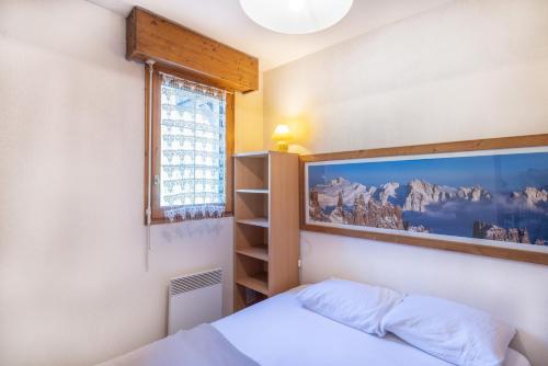 a bedroom with a bed with a picture on the wall at Le jardin des neiges in Praz-sur-Arly