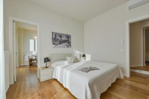 フィレンツェにあるApartments Florence - Ponte Vecchio Guelfoの白いベッドとウッドフロアのベッドルームが備わります。
