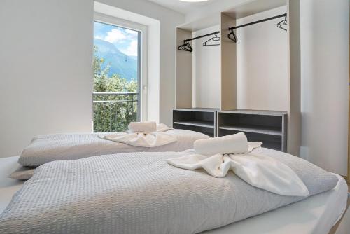 two beds in a white room with a window at Haus Weinblick Apt 5 in Magrè allʼ Adige