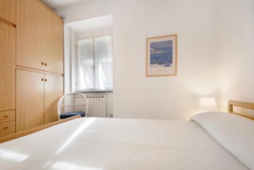 a white bedroom with a bed and a chair at Nonna Adele in Sestri Levante
