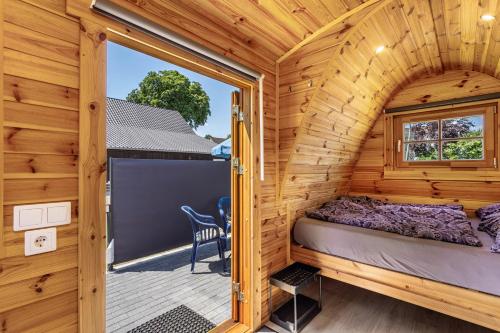 a bedroom in a wooden cabin with a large window at Campingpod Auf Der Alpakawiese in Arnsberg