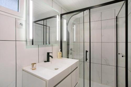 a white bathroom with a sink and a shower at Casa Estrela Do Norte in Ponta Delgada