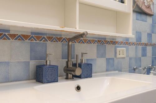 a sink in a bathroom with a faucet and two blue containers at Villa Lorenz in Putignano