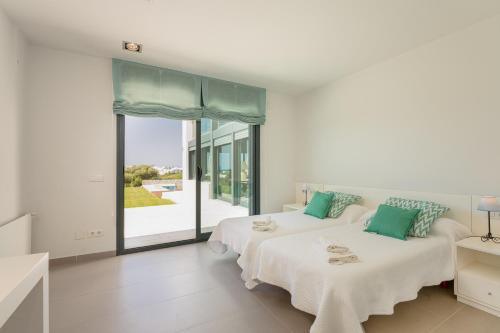 two beds in a white room with a large window at Villa Canutells Ref 27 in Mahón