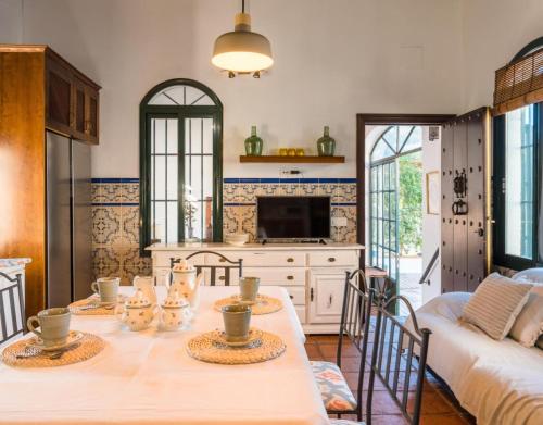 a kitchen with a table with chairs and a couch at Finca Gorriones 25 minutos Sevilla in El Garrobo