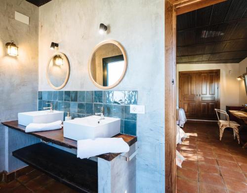 a bathroom with two sinks and a mirror at Finca Gorriones 25 minutos Sevilla in El Garrobo