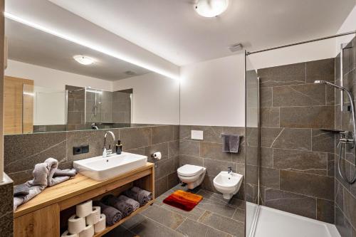a bathroom with a sink and a toilet and a shower at Krämerhof Apt Peitlerkofel in Rodengo