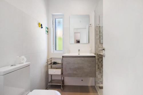 a white bathroom with a sink and a mirror at Villa Lynn - Quadradinhos in Almancil