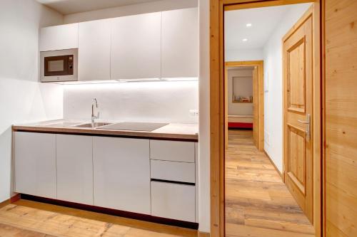 a kitchen with white cabinets and a sink and a hallway at Chalet Pieri - Appartamento Bedogn in Bormio