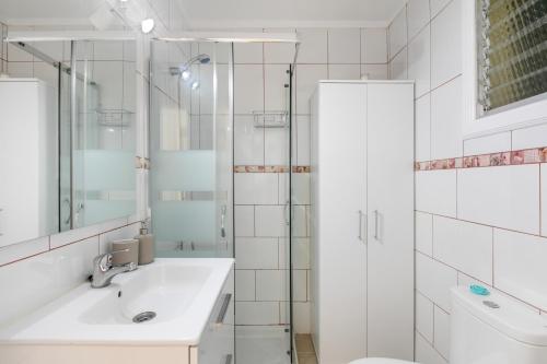 a white bathroom with a sink and a shower at Coral Beach in Bajamar