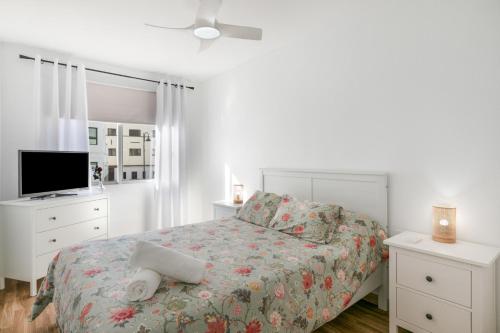 a white bedroom with a bed and a tv at Coral Beach in Bajamar