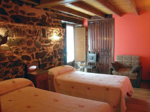 a room with two beds and a stone wall at El Mirador Del Pedroso in Barbadillo del Pez