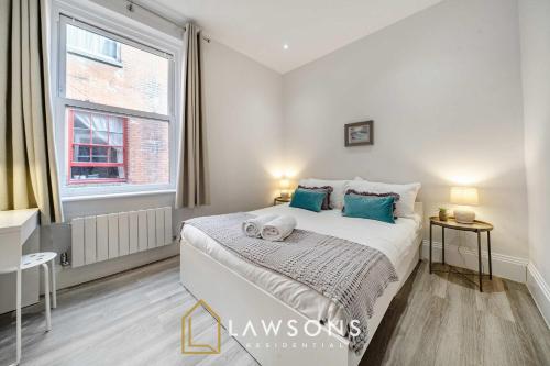 a bedroom with a bed with blue pillows and a window at Sea You Soon I Seafront Stay in Portsmouth