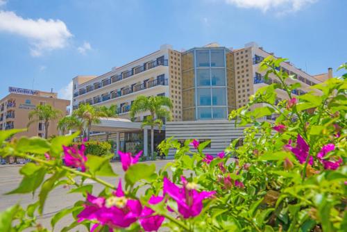 a building with pink flowers in front of it at Tsokkos Gardens Hotel in Protaras
