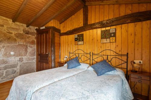 a bedroom with a bed in a room with wooden walls at Casa Rural Magina in Fornelos de Montes