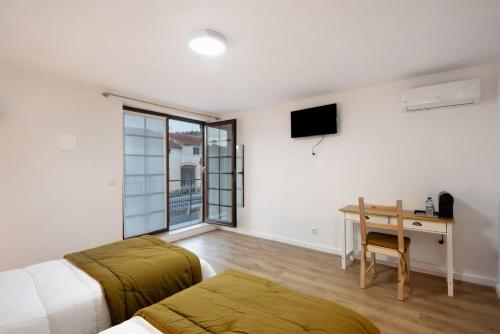 a bedroom with a bed and a desk with a table at Df Alojamentos e Suites in Coimbra