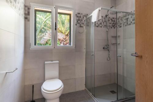 a bathroom with a toilet and a shower and a window at Oleanda in Alcudia