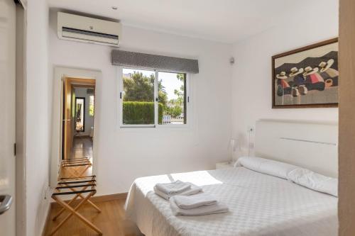 a white bedroom with a bed and a window at Oleanda in Alcudia