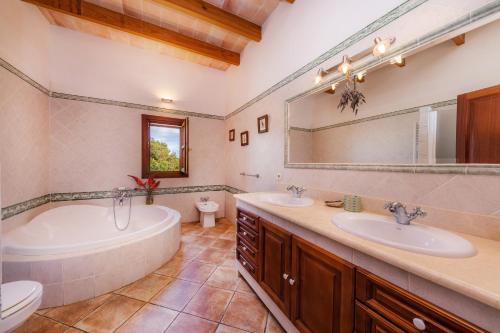 a bathroom with two sinks and a tub and a toilet at Turó de na Roca in S'Horta