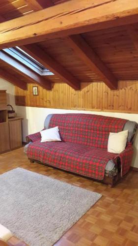 a red couch in a room with wooden ceilings at Mansarda le Chateau in Aymavilles