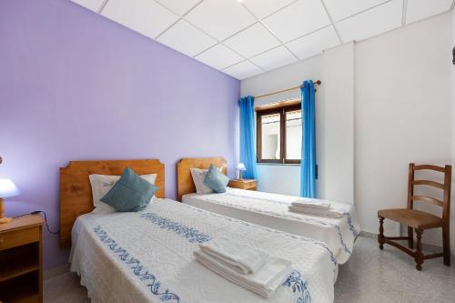 a bedroom with two beds and a chair and a window at Apartment T2 Malveiro in Odeceixe