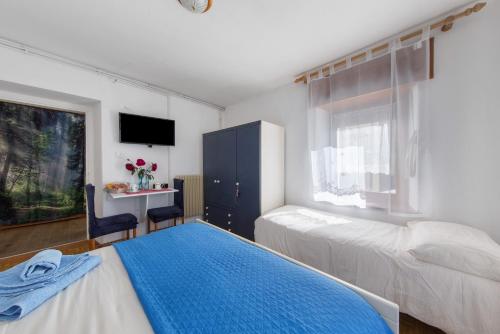 a bedroom with two beds and a desk and a window at Affittacamere Angelina in San Pietro di Cadore