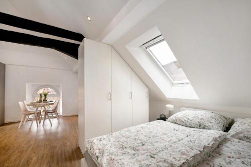 a white bedroom with a bed and a table at Adlernest mit Weinbergblick in Trittenheim