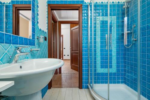 a blue tiled bathroom with a sink and a tub at Villetta Confortevole in San Teodoro