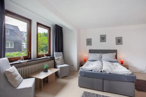 a bedroom with a bed and a chair and windows at Gästehaus Roth in Willingen