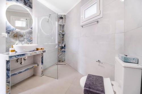 a white bathroom with a sink and a mirror at Scorpios View Meganisi in Meganisi