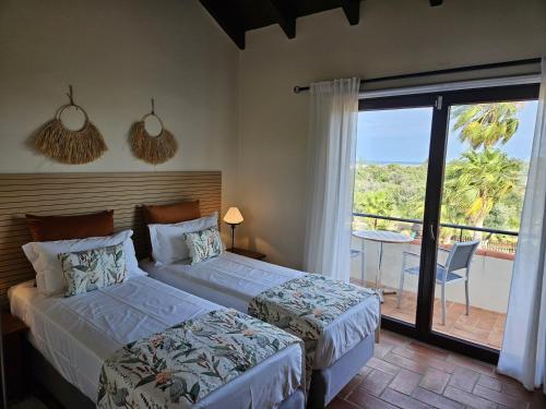 two beds in a bedroom with a view of a balcony at Villa Laguna - Charmy Villa in Moncarapacho