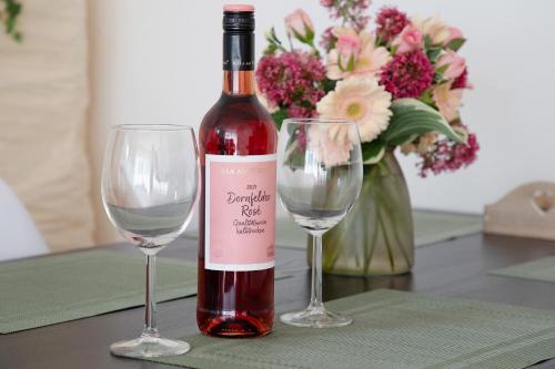 a bottle of wine and two glasses on a table at Ferienwohnung am Hof in Zwiefalten