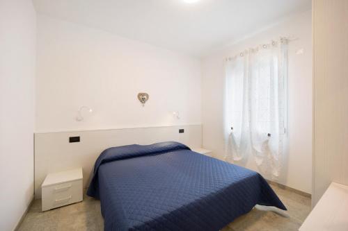 a white bedroom with a blue bed and a window at Antichi Ricordi - La Stalla in Marina di Andora