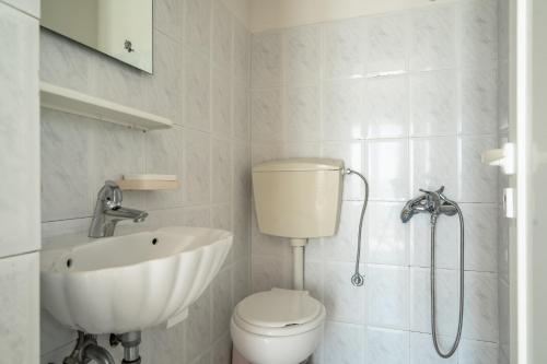 a white bathroom with a toilet and a sink at Angela sea view 4 in Kefallonia