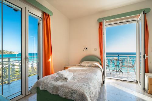 a bedroom with a bed and a balcony with the ocean at Angela sea view 4 in Kefallonia