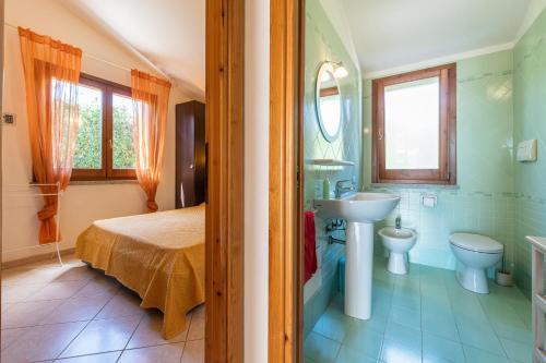 a bathroom with a bed and a sink and a toilet at Domixedda in Costa Rei