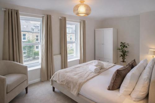 a bedroom with a bed and a chair and windows at Duplex Apartment - Central Harrogate Apartment in Harrogate