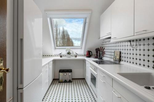 a kitchen with white cabinets and a window at Untersee Appartements in Moos